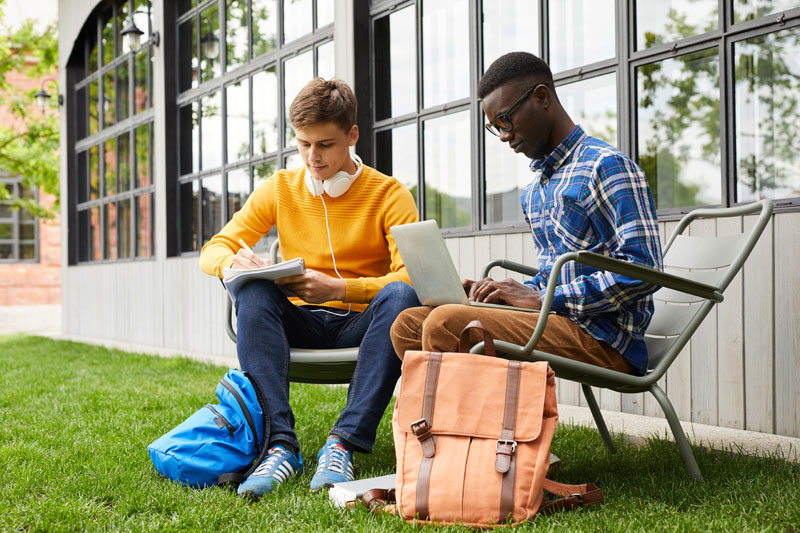 Two college students working on their homework in front of a private college