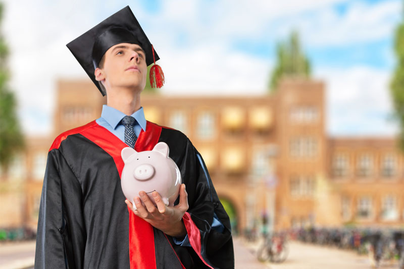college graduate holding savings piggy bank