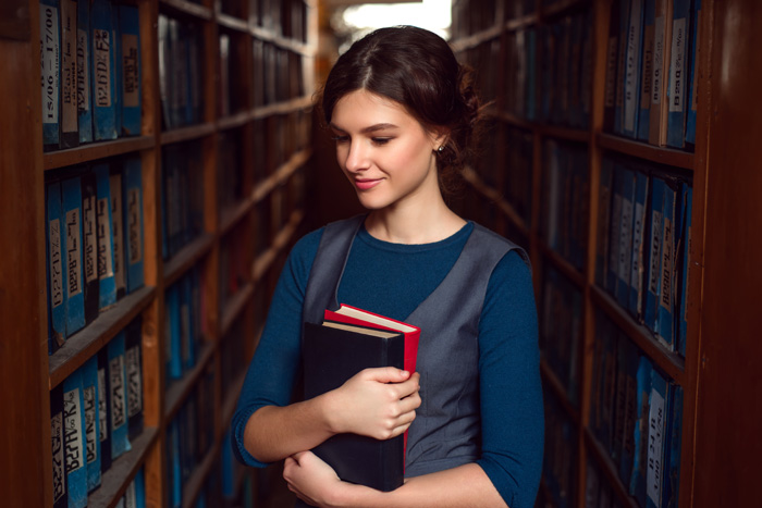 College student researching scholarship essay questions at library